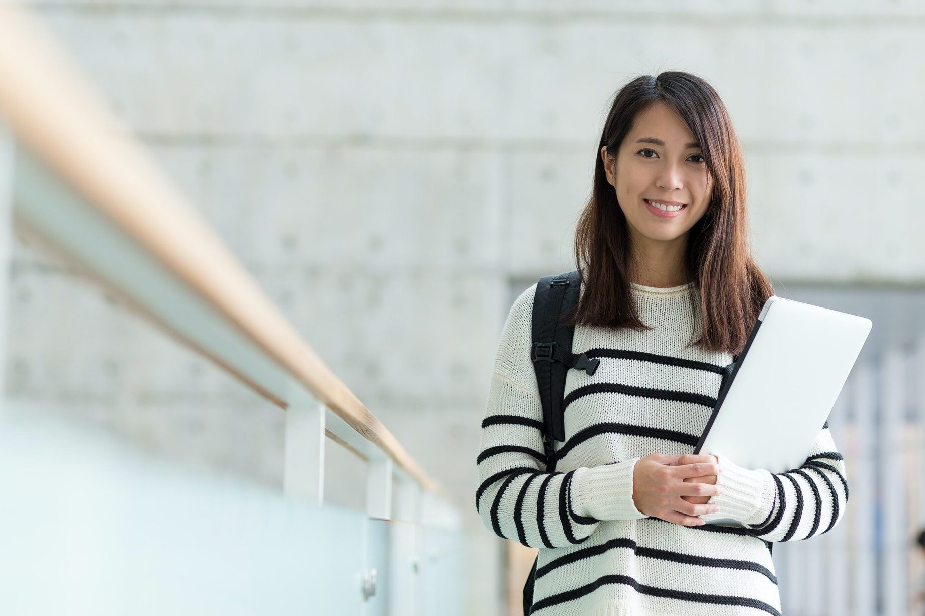 A JL Institution learner holding a laptop on campus