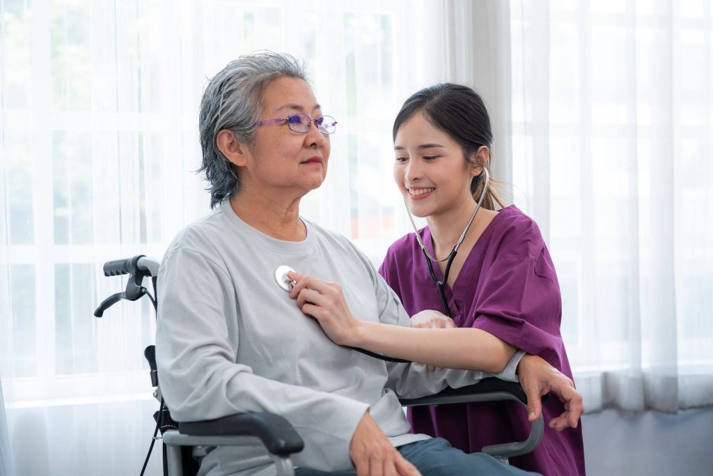 Caregiver assisting a senior with a walking frame, one of the daily living skills taught in the course